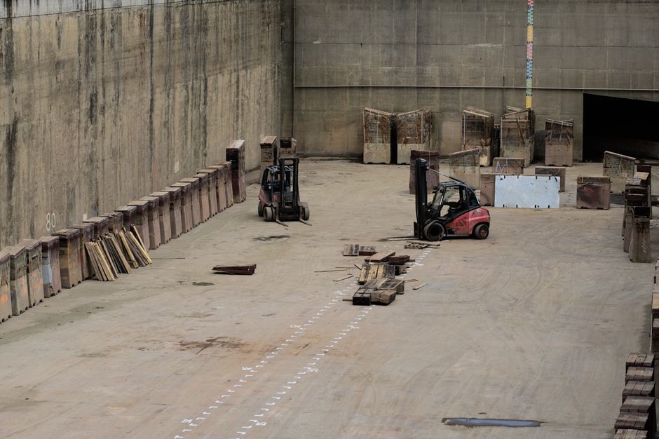 An indoor loading bay area with a concrete floor, used for home relocation and furniture transport. Two small electric forklifts are positioned nearby, one black and red, and the other black. Along th