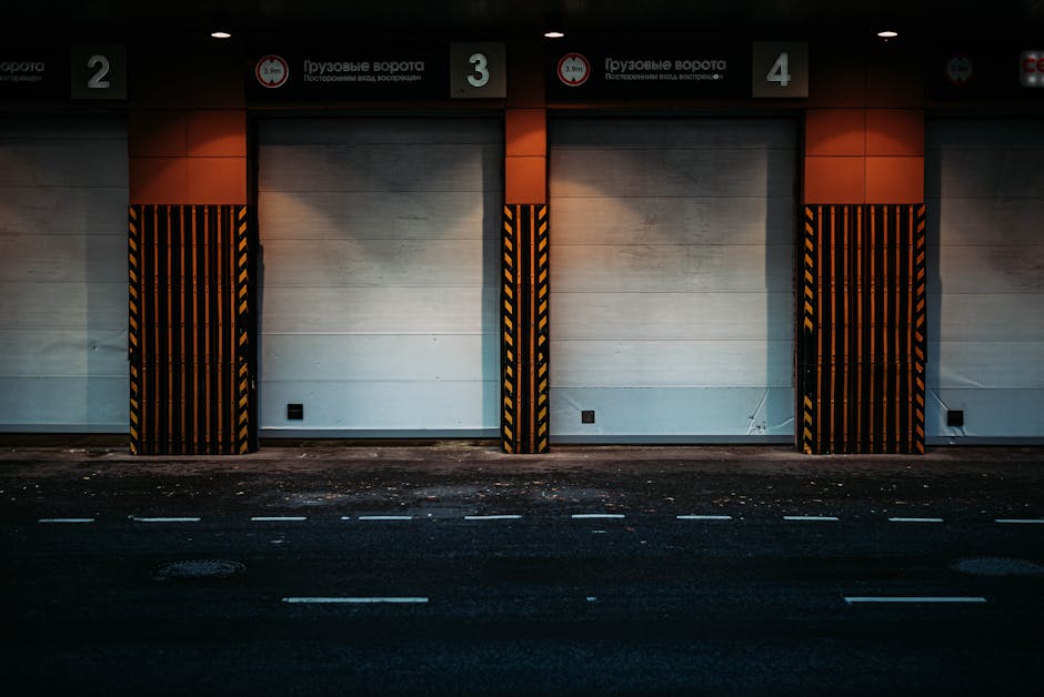 An indoor loading bay area with a concrete floor, used for home relocation and furniture transport. Two small electric forklifts are positioned nearby, one black and red, and the other black. Along th